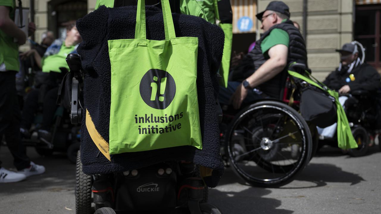 Un sac de l'Initiative pour l'inclusion est accroché à un fauteuil roulant lors du lancement de l'initiative populaire fédérale "Pour l'égalité des personnes handicapées", le jeudi 27 avril 2023 à Berne. [Keystone - Anthony Anex]