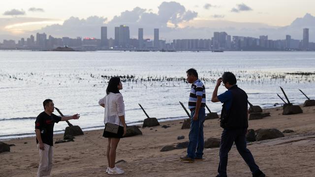 The Xiamen city in China is seen in the background as a people walk next to anti landing spikes installed at the coast of Kinmen County, Taiwan, 03 July 2024. Taiwan has demanded the release of a Taiwanese fishing boat seized by the Chinese coastguard and taken to a port in mainland China on 02 July 2024. The Dajinman 88 was intercepted by two Chinese vessels near the Kinmen archipelago, an area controlled by Taiwan, according to a statement by the Taiwanese coastguard administration. [EPA/Keystone - RITCHIE B. TONGO]