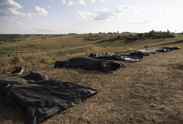 Des sacs mortuaires sont alignés alors que des membres du groupe de recherche ukrainien "Platsdarm" travaillent à l'exhumation et à l'identification des corps de soldats russes morts près d'une ligne de front dans la zone de Bakhmut, région de Donetsk, Ukraine, le 1er août 2024. [KEYSTONE - NIKOLETTA STOYANOVA]