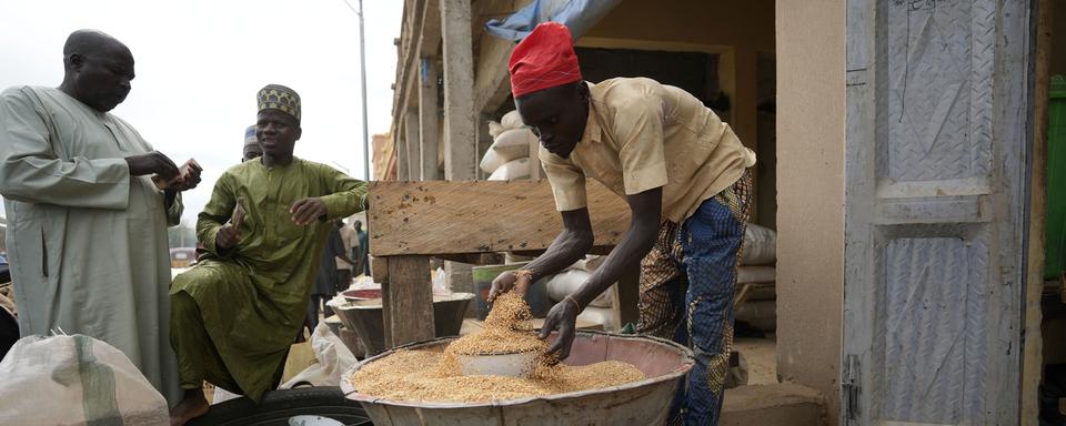 Un homme vent du grain dans un marché international au Nigéria. Le pays africain a introduit un programme d'indépendance céréalière dès avant l'invasion de l'Ukraine. [Keystone/AP Photo - Sunday Alamba]