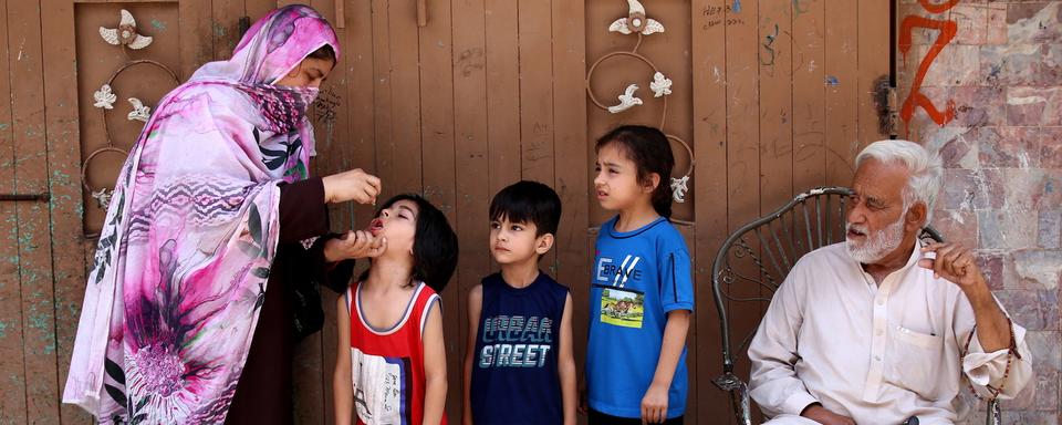 Une travailleuse de santé itinérante vaccine des enfants contre la polio au Pakistan. [Keystone/EPA - Arshad Arbab]