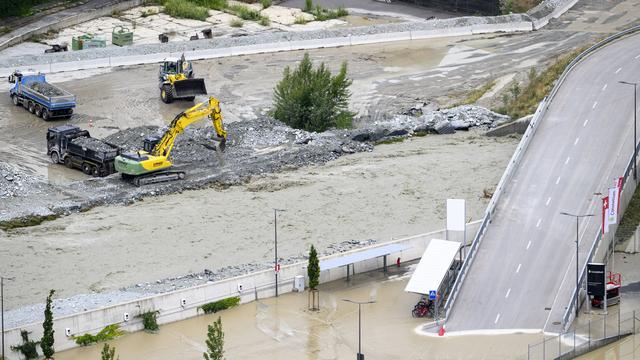 Des pelleteuses dégagent le gravier qui a remonté le niveau de la rivière après les récentes inondations causées par le débordement du Rhône sur le plateau en Valais. [Keystone - Jean-Christophe Bott]