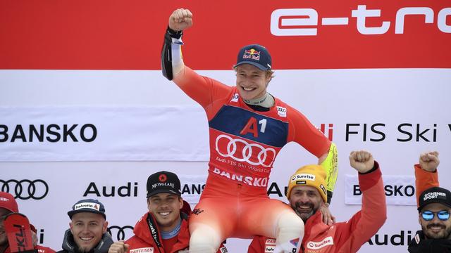 Marco Odermatt célèbre sa victoire avec son équipe lors de l'épreuve de Coupe du monde de slalom géant de Bansko. [KEYSTONE - VASSIL DONEV]