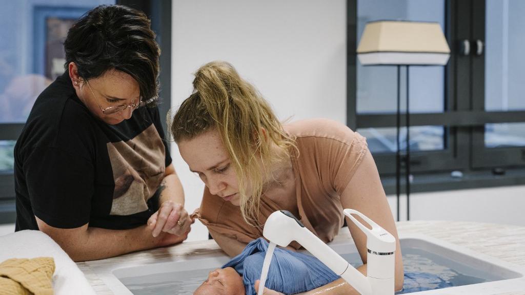 Une sage-femme baignant un bébé. [Keystone - Denis Meyer / Hans Lucas]