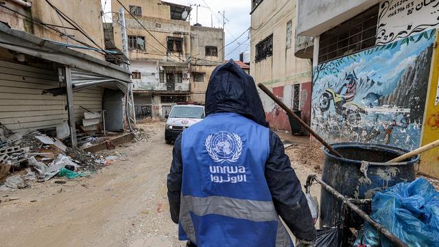 Un homme portant une veste de l'UNRWA collecte des déchets dans la ville de Jénine, en Cisjordanie, le 30 janvier 2024. [AFP - JAAFAR ASHTIYEH]