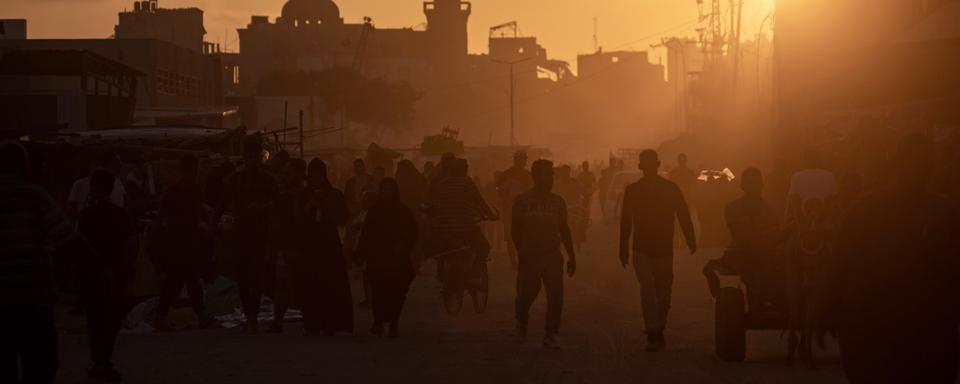 Des Palestiniens dans une rue détruite du camp de réfugiés de Khan Younès à Gaza. [Keystone/EPA - Haitham Imad]