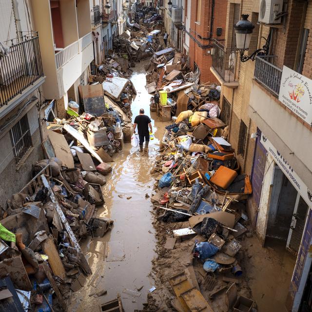 Mardi 5 novembre: A Paiporta, une personne marche dans la rue au milieu des décombres liés aux inondations dans la région de Valence. [Keystone - Emilio Morenatti]