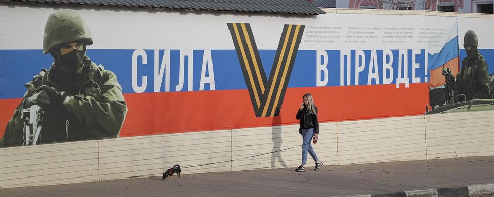 Une femme devant un message de propagande ''Le Pouvoir est dans la vérité'' en Russie. [Keystone/EPA - Maxim Shipenkov]