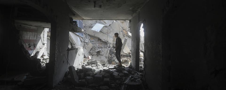 Un Palestinien de profil dans les décombres de Rafah. [Keystone/AP Photo - Ismael Abu Dayyah]