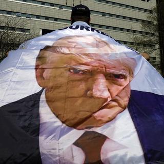 Un soutien de Trump avec un drapeau géant à son image. [Keystone/EPA - Peter Foley]