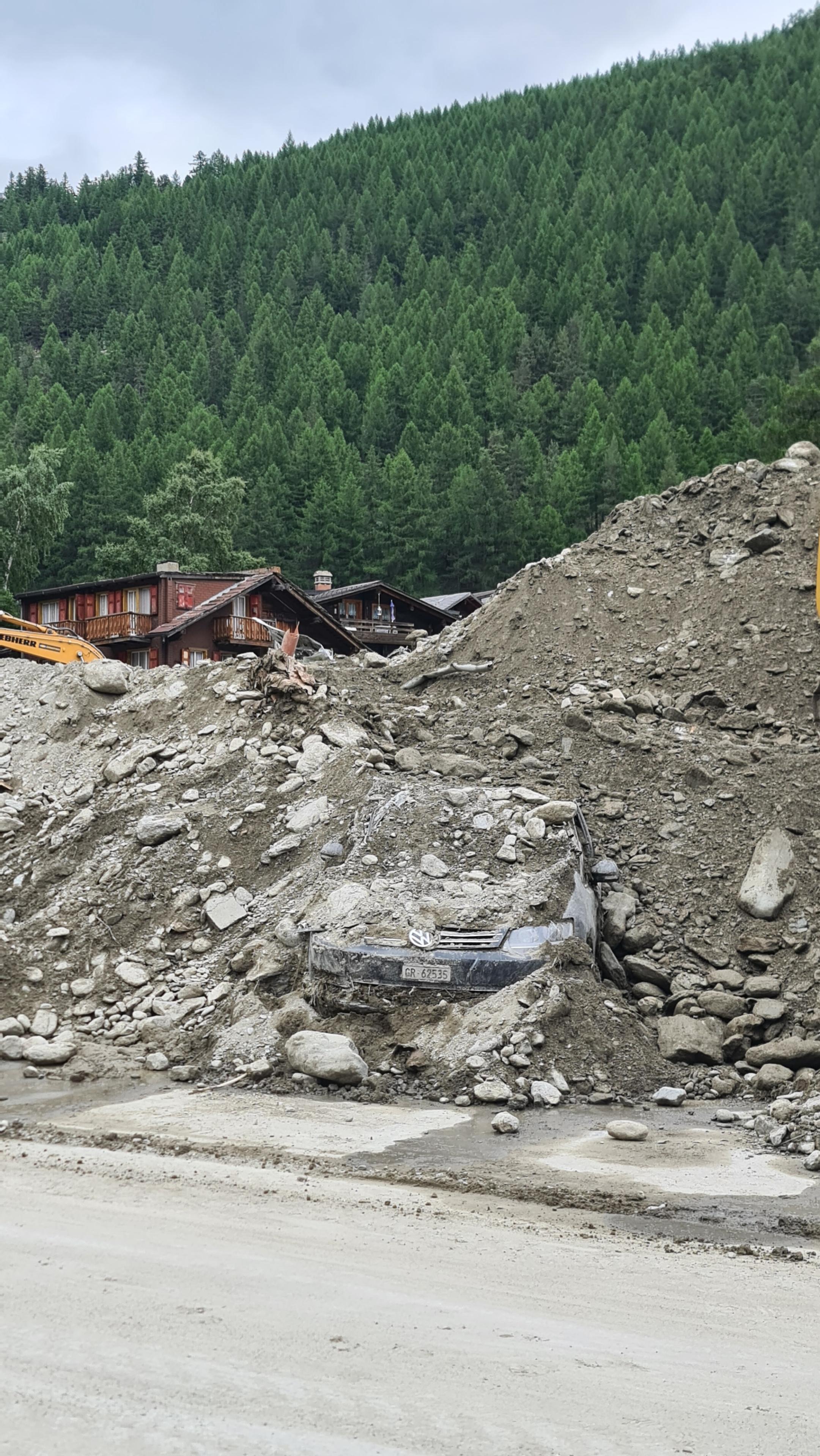 La route cantonale a été déblayée, mais des tas de matériaux mélangés à de la boue recouvrent encore les trottoirs, le 2 juillet 2024. [RTS - EMILIEN VERDON]