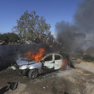 Une voiture brûle après avoir été touchée par une frappe israélienne à Gaza. [Keystone - AP Photo/Hatem Ali]