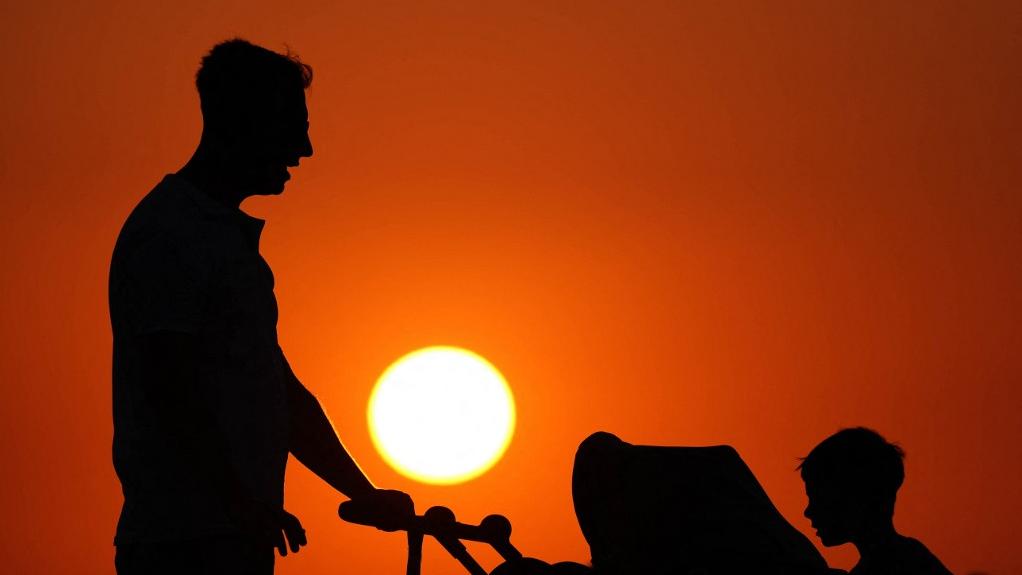 Un homme pousse une poussette accompagné d'un garçon, à Izmir en Turquie. [Anadolu via AFP - Berkan Cetin]