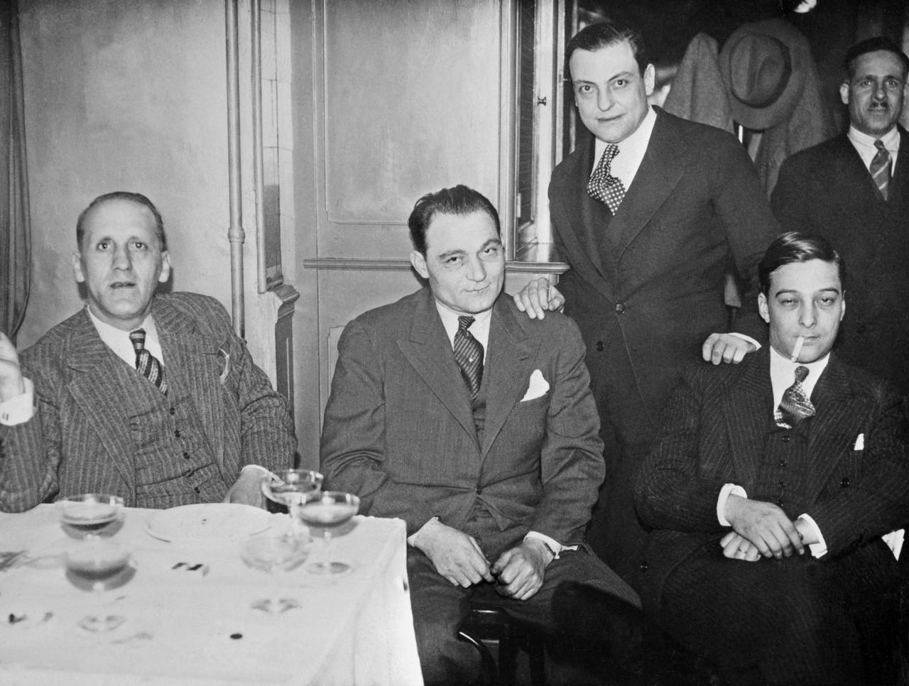 Simon Sabiani (G), politicien marseillais, avec Paul Bonnaventure Carbone (C) et François Spirito (D debout, main sur l'épaule), figures de la pègre marseillaise des années trente, en mai 1934. [AFP - STF]