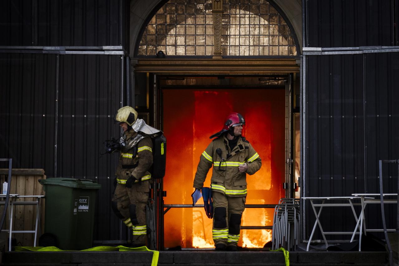 Des pompiers sortent du bâtiment en feu. [KEYSTONE - IDA MARIE ODGAARD]