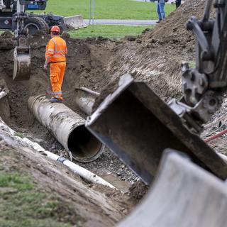 Un ouvrier s'affaire à réparer la conduite d'eau potable qui a cédé à Genève, rendant l'eau de 9 communes impropre à la consommation. [Keystone - Martial Trezzini]