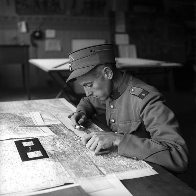 Un chef de détachement de l'armée suisse en service actif pendant la Seconde Guerre mondiale se penche sur une carte [KEYSTONE/PHOTOPRESS-ARCHIV - Hans Gerber]