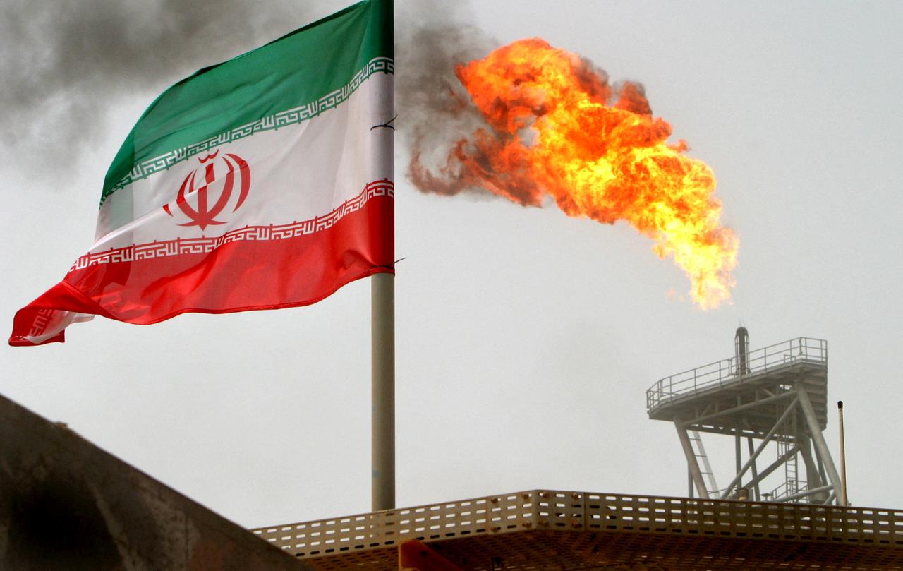 Une torche de gaz sur une plate-forme de production pétrolière est visible aux côtés d'un drapeau iranien, le 25 juillet 2005 (image prétexte). [REUTERS - Raheb Homavandi]