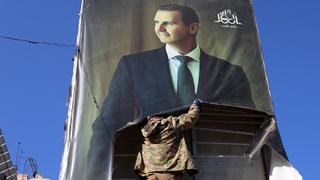 Un rebelle arrache un portrait du président syrien Bachar al-Assad à Alep. [AFP - MOHAMMED AL-RIFAI]