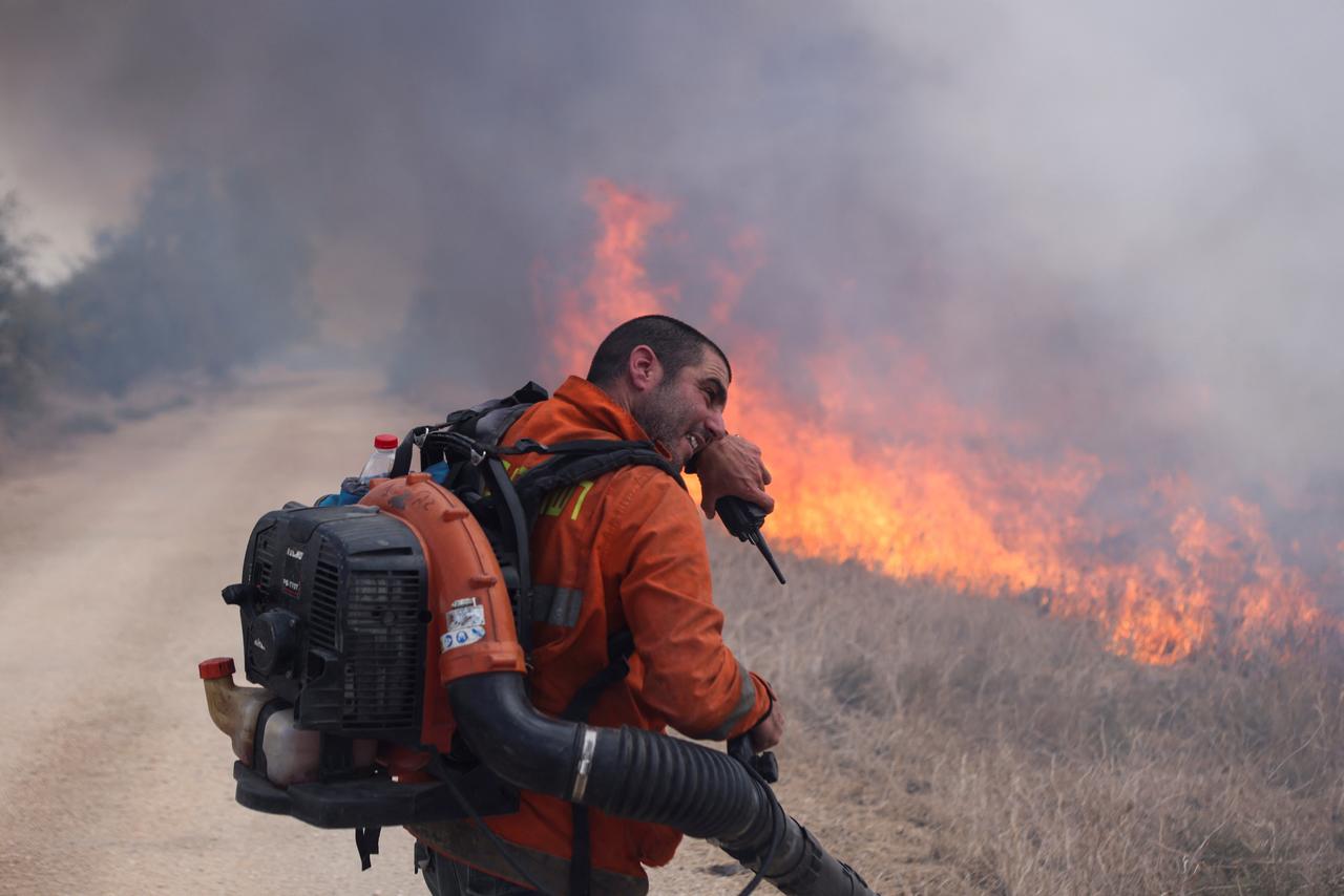 Un homme essaie d'éteindre un incendie après le tir d'une roquette du Liban vers le plateau de Golan. [REUTERS - Jim Urquhart]