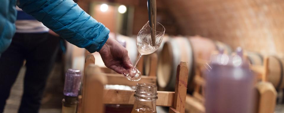 Une personne remplit un verre de vin en Valais. [Keystone - Gaetan Bally]