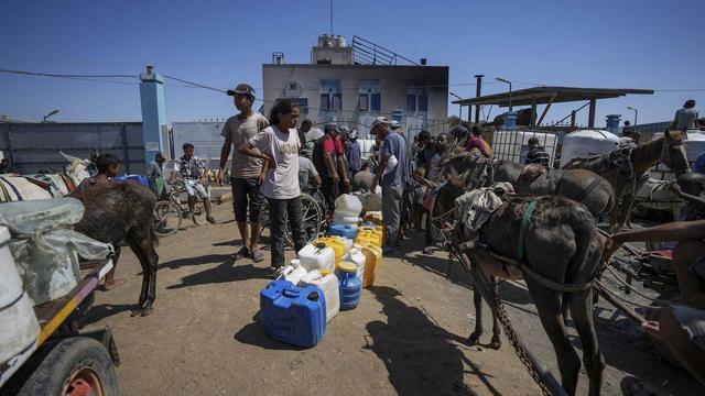 Des Palestiniens déplacés font la queue pour aller chercher de l'eau, le 23 août 2024. [Keystone]