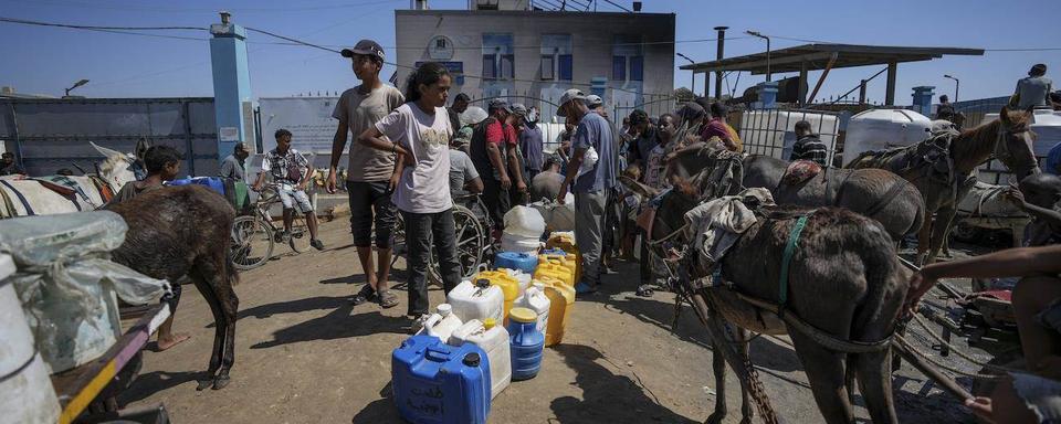 Des Palestiniens déplacés font la queue pour aller chercher de l'eau, le 23 août 2024. [Keystone]