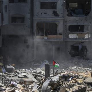 Un drapeau palestinien dans les ruines après une frappe israélienne sur le camp al-Bureij à Gaza. [Keystone/EPA - Mohammed Saber]
