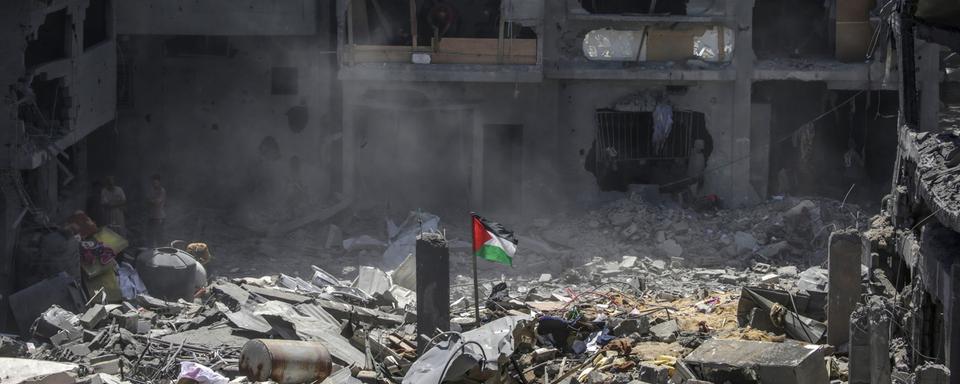 Un drapeau palestinien dans les ruines après une frappe israélienne sur le camp al-Bureij à Gaza. [Keystone/EPA - Mohammed Saber]