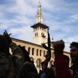 Des rebelles armés tirent sur des armes et célèbrent devant la mosquée des Omeyyades dans le centre de Damas, Syrie, 08 décembre 2024. [KEYSTONE - MOHAMMED AL RIFAI]