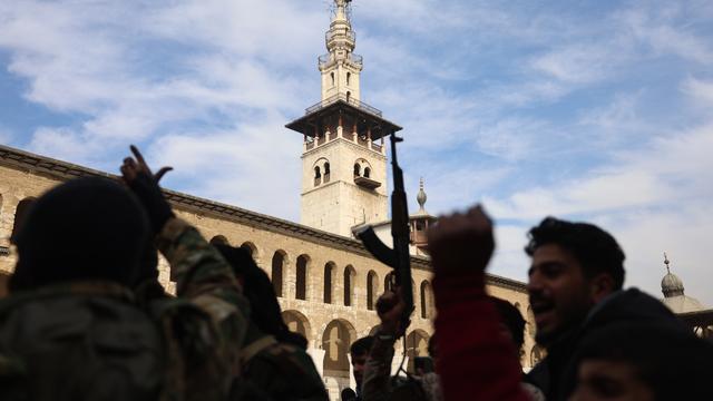 Des rebelles armés tirent sur des armes et célèbrent devant la mosquée des Omeyyades dans le centre de Damas, Syrie, 08 décembre 2024. [KEYSTONE - MOHAMMED AL RIFAI]