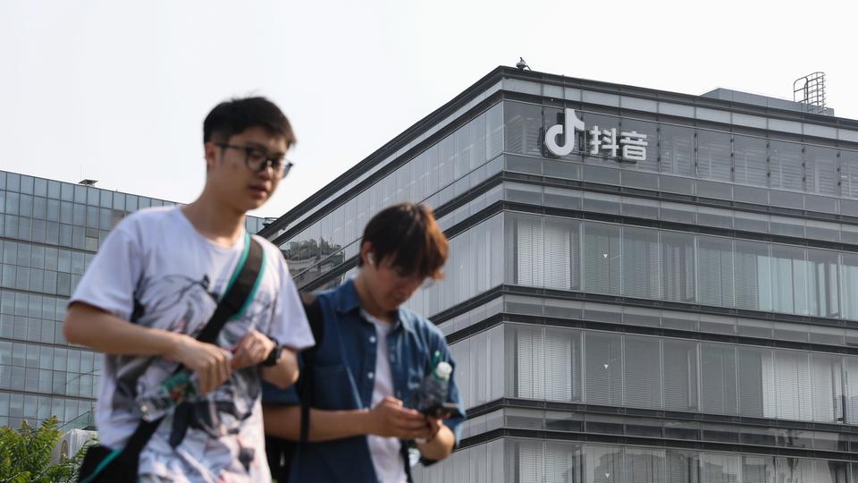 Des jeunes gens devant un bâtiment de ByteDance, l'entreprise chinoise à qui appartient le réseau TikTok. [Keystone/EPA - Wu Hao]