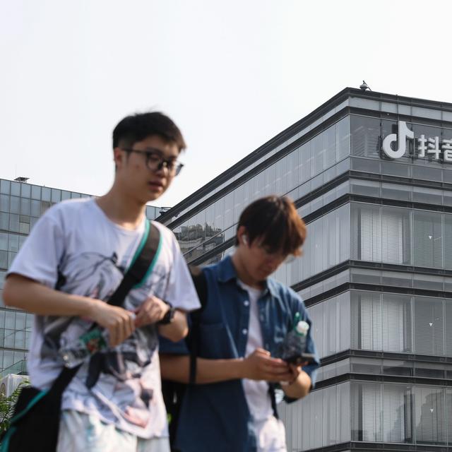 Des jeunes gens devant un bâtiment de ByteDance, l'entreprise chinoise à qui appartient le réseau TikTok. [Keystone/EPA - Wu Hao]