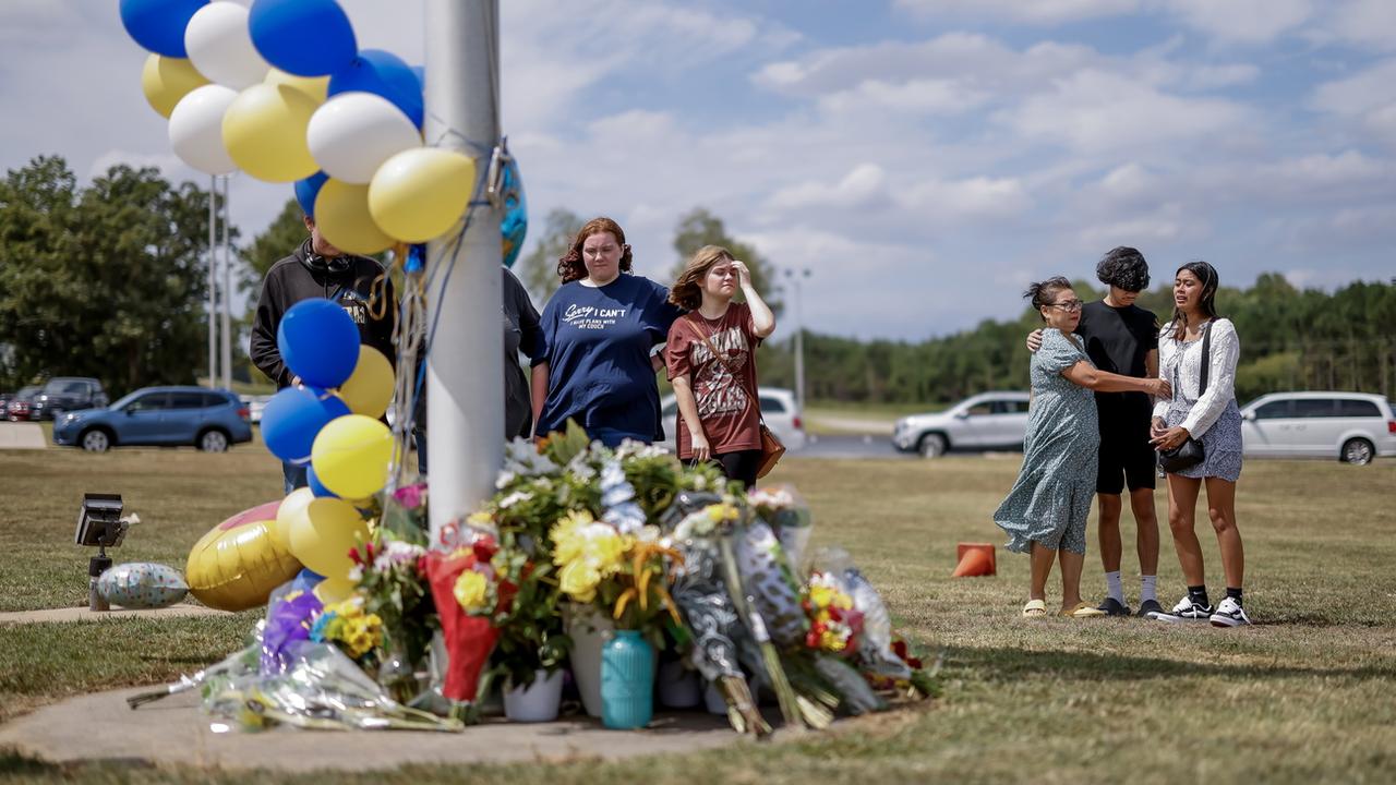 Des proches des victimes de la fusillade de l'école secondaire Apalachee à Winder, aux Etats-Unis, se recueillent devant un mémorial improvisé [Keystone/EPA - Erik S. Lesser]