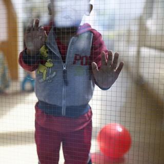 Un jeune enfant avec un ballon, photographié lors d'une visite du centre pour requérants d'asile Bergruh, en mai 2016, à Amden. [Keystone - GIAN EHRENZELLER (Montage: cellule data)]