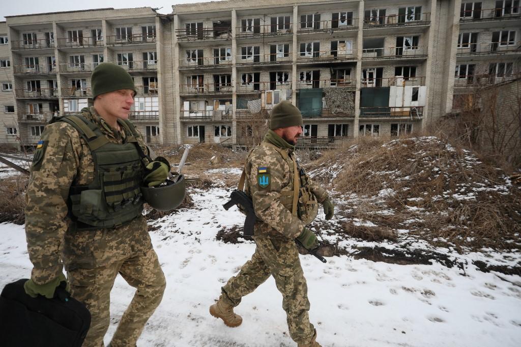 Des soldats ukrainiens marchent devant un bâtiment endommagé à Mariïnka, le 7 février 2022. La ville était alors le théâtre d'affrontements avec les séparatistes pro-russes. [AFP - OLEKSII FILIPPOV]