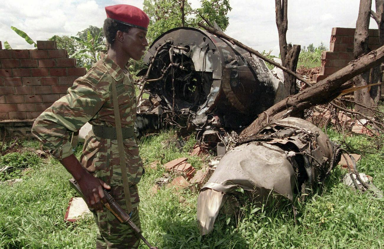 Le 23 mai 1994, un combattant du FPR marche devant la carcasse de l'avion présidentiel qui s'est écrasé le 6 avril. [KEYSTONE - JEAN-MARC BOUJU]