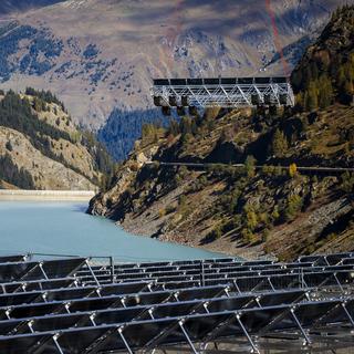 Des panneaux solaires flottants en train d'être installés dans un réservoir d'eau alpin de la commune de Bourg-Saint-Pierre (VS). [Keystone - Valentin Flauraud]