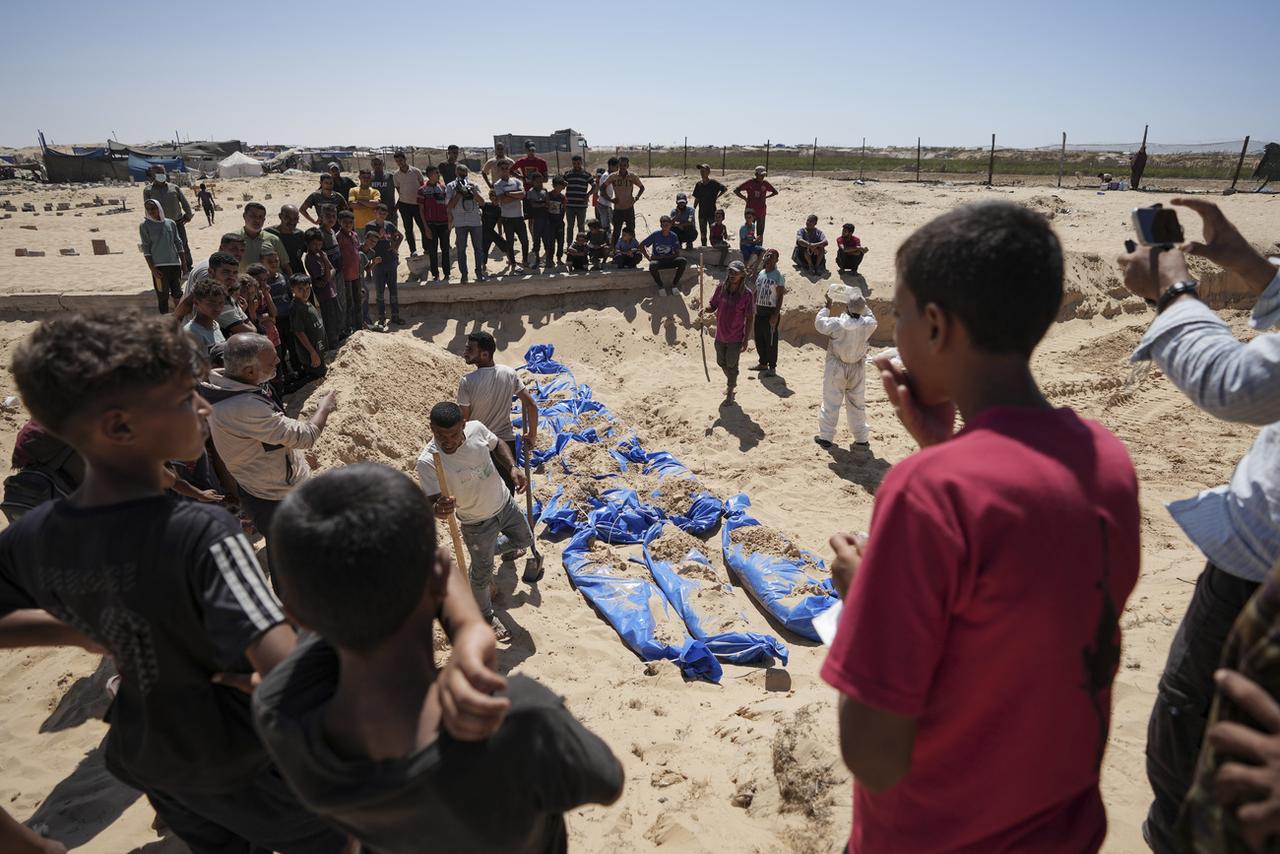 Des personnes enterrent des corps non identifiés de Palestiniens rendus par Israël dans un cimetière près de Khan Younès. [KEYSTONE - ABDEL KAREEM HANA]