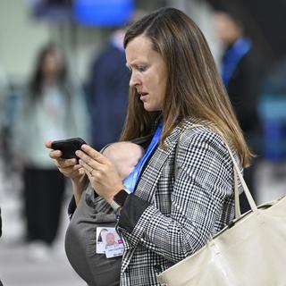 Un mère portant son enfant à la COP29. [AFP - Utku Ucrak / ANADOLU /]