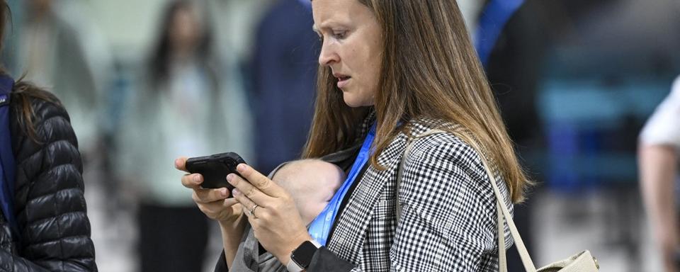 Un mère portant son enfant à la COP29. [AFP - Utku Ucrak / ANADOLU /]