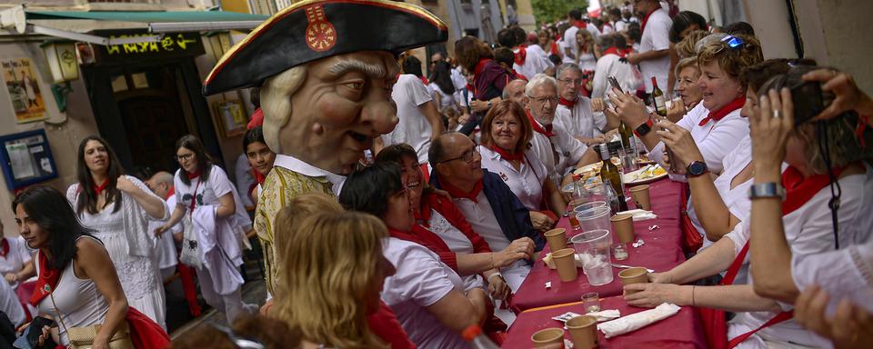 Un membre du "défilé des géants" pose avec des festivaliers lors des fêtes de San Fermín à Pampelune, en Espagne, le lundi 8 juillet 2024. [Keystone - AP Photo/Alvaro Barrientos]