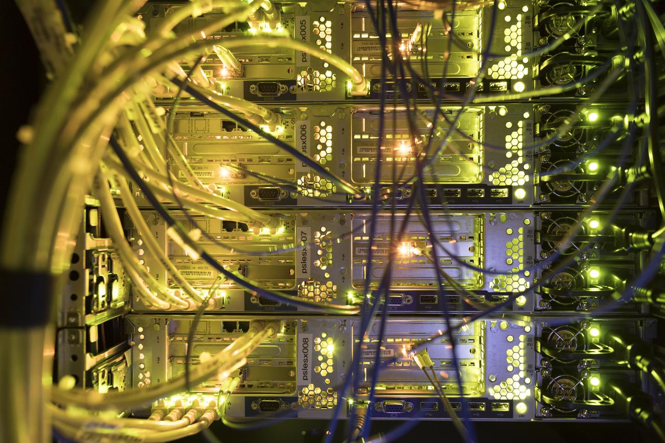 Vue arrière d'un rack avec des éléments de réseau: LED, câbles à fibre optique et commutateurs dans la salle des serveurs d'une entreprise à Zurich, en Suisse, le 4 juillet 2017. [KEYSTONE - GAETAN BALLY]