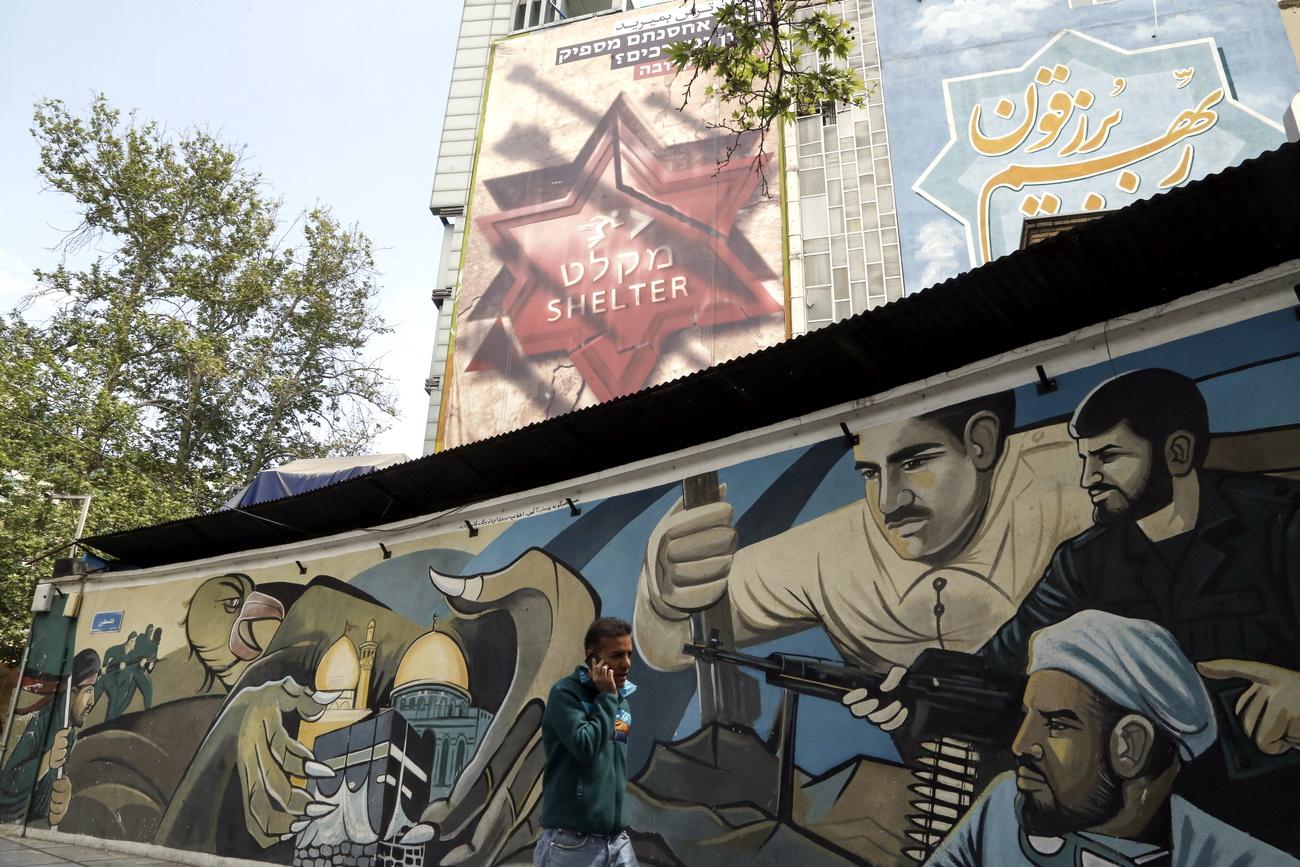 Un homme passe devant des affiches et peintures murales anti-israéliennes, le 12 avril 2024 à Téhéran. [KEYSTONE - ABEDIN TAHERKENAREH]