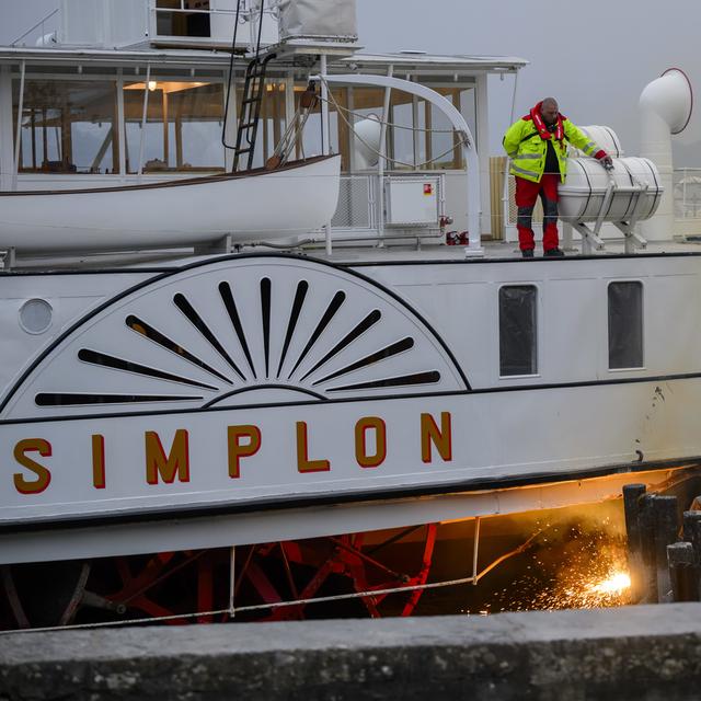 Des ouvriers sécurisent le Simplon, un bateau centenaire ''Belle Epoque'' de la CGN à Ouchy. [Keystone - Jean-Christophe Bott]