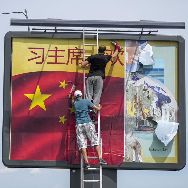 Des ouvriers qui installent un drapeau chinois à Belgrade. [Keystone/AP Photo - Darko Vojinovic]