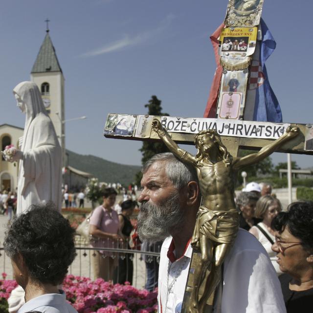 Des pèlerins avec des statues de la Vierge et de Jésus crucifié lors d'une procession en Bosnie-Herzégovine. [Keystone/AP Photo - Amel Emric]