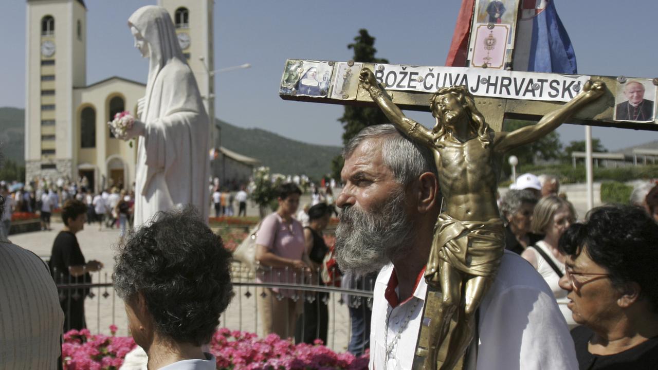 Des pèlerins avec des statues de la Vierge et de Jésus crucifié lors d'une procession en Bosnie-Herzégovine. [Keystone/AP Photo - Amel Emric]