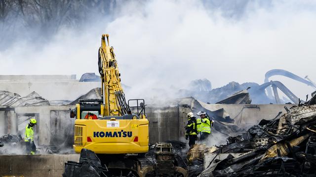 Des pompiers travaillent autour des décombres après l'incendie d'une ferme é Bottens. [KEYSTONE - JEAN-CHRISTOPHE BOTT]