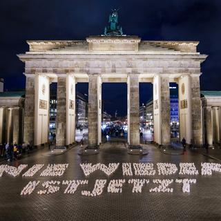 Des bougies forment le slogan "Plus jamais ça", lors d'une manifestation devant la porte de Brandebourg à Berlin, en Allemagne, le 26 janvier 2024, un jour avant la Journée internationale de commémoration de l'Holocauste. [Keystone - EPA/CLEMENS BILAN]